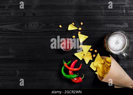 Snack for party, chips, nachos with sauces and mug of beer on a black background. Top view, copy space Stock Photo
