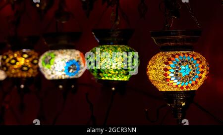 Selective focus of Oriental lantern in row with different mosaic art and colors. Stock Photo