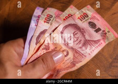 Man hand flip thai baht banknote, the official currency of Thailand. On front side the portrait of the Rama or King,  Close up Paper Money of Thailand Stock Photo