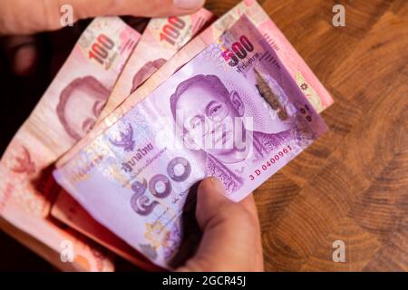 Man hand flip thai baht banknote, the official currency of Thailand. On front side the portrait of the Rama or King,  Close up Paper Money of Thailand Stock Photo