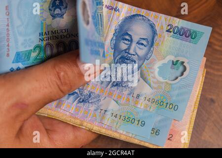 Male hand holds a fan of  Vietnames Dong banknote, the currency of Vietnam.  Close up Polymer Money of Vietnam. 20000 Dong or VND in male hand. In fro Stock Photo