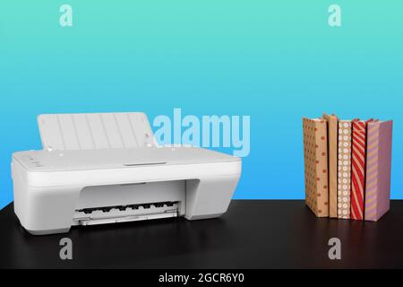 Compact laser printer on black desk against blue background Stock Photo