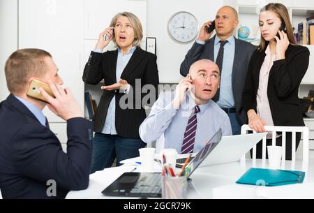 Crisis in the modern office: managers are urgent negotiations by phones Stock Photo