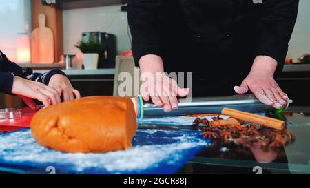 Mother and daughter making gingerbread cookies in the kitchen at home. Family culinary and traditions concept. Stock Photo