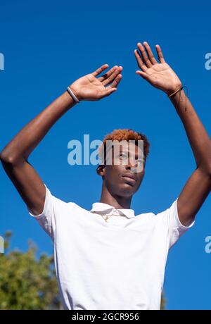 Young man with colorful hair holding his hands up Stock Photo
