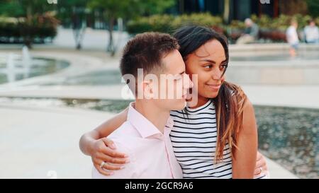 Handsome man and attractive black woman having date in a modern city park. They talking and man showing her something around. Stock Photo