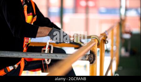Construction worker wearing safety harness and safety line working at high place Stock Photo