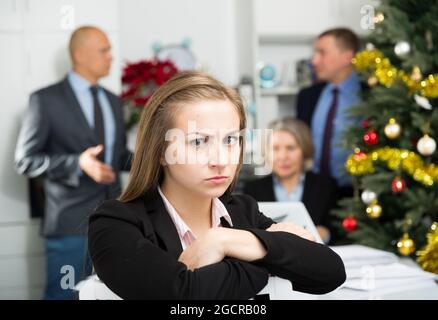 Business team tensely solving problems in office with upset woman foreground Stock Photo