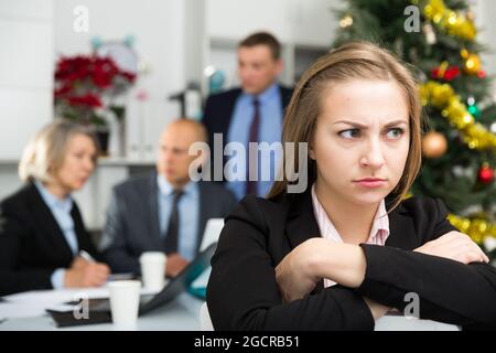 Business team tensely solving problems in office with upset woman foreground Stock Photo