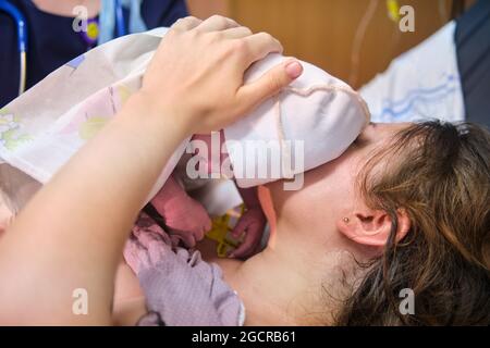 A woman who gave birth to a newborn baby boy. Laying the child out on the mother chest immediately after childbirth Stock Photo