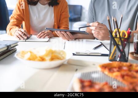 group of business people talking about project and prepare pizza and potato chips for having lunch in corporate together in office Stock Photo