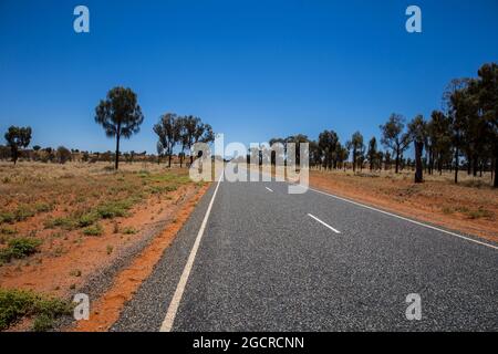 The road to nowhere at the Australian Outback. The stuart highway on the way to the Uluru or Ayers Rock. Empty street through the wide open flat austr Stock Photo