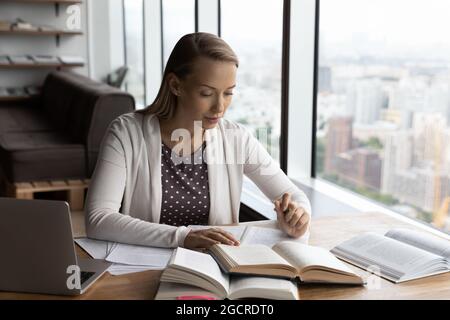 Focused millennial female student studying at home workplace Stock Photo