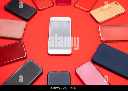 Choice of multicolored plastic back covers for mobile phones on red background with a smart phone on the side Stock Photo