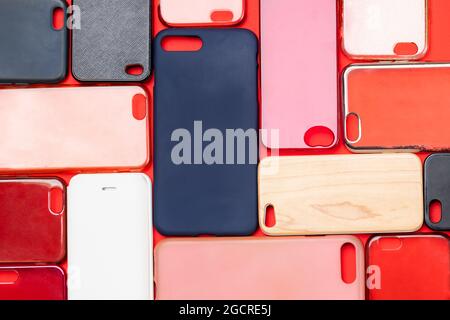 Pile of multicolored plastic back covers for mobile phone. Choice of smart phone protector accessories on red background. A lot of silicone phone back Stock Photo