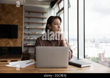 Thoughtful business owner woman looking out of window at city Stock Photo