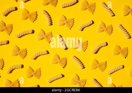 Uncooked curly pasta pattern on yellow background. Traditional dry raw macaroni pattern. Nobody Stock Photo