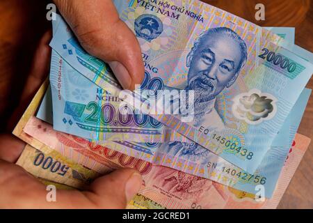 Male hand holds a fan of  Vietnames Dong banknote, the currency of Vietnam.  Close up Polymer Money of Vietnam. 20000 Dong or VND in male hand. In fro Stock Photo