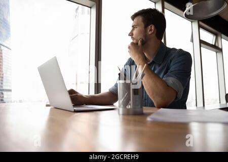 Thoughtful employee, business man, manager looking out of window Stock Photo