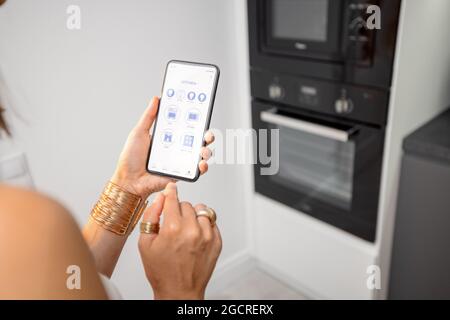 Controlling smart devices with phone on the kitchen Stock Photo