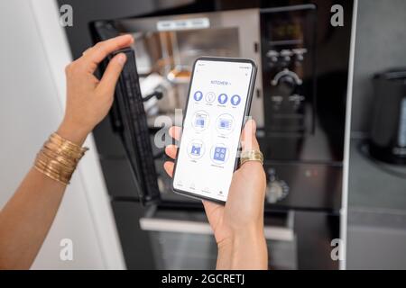 Controlling smart devices with phone on the kitchen Stock Photo