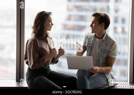 Team members, coworkers sitting at panoramic window, discussing work project Stock Photo