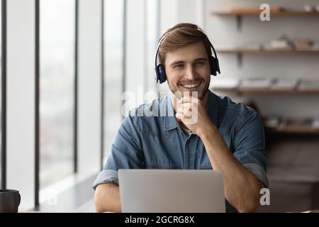 Happy student guy in headphones using laptop for distance studying Stock Photo