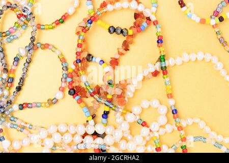Necklaces and bracelets made from multicolored beads and pearls on a golden background. Stock Photo