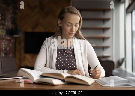 Serious college or internship student studying heap of books Stock Photo