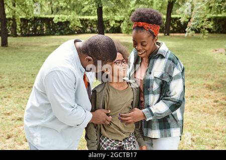 Happy young parents tickling their cute son while having fun in park Stock Photo