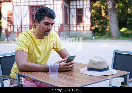 Tourist using the smartphone sitting on a bar summer terrace. Stock Photo