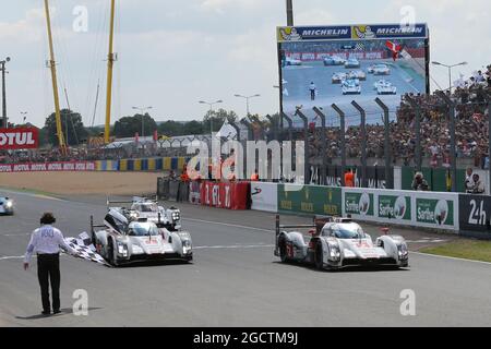 Race winner Marcel Fassler (SUI) / Andre Lotterer (GER) / Benoit Treluyer (FRA) #02 Audi Sport Team Joest Audi R18 e-tron quattro Hybrid takes the chequered flag at the end of the race ahead of second placed Lucas di Grassi (BRA) / Tom Kristensen (DEN) / Marc Gene (ESP) #01 Audi Sport Team Joest Audi R18 e-tron quattro Hybrid. FIA World Endurance Championship, Le Mans 24 Hours, Race, Sunday 15th June 2014. Le Mans, France. Stock Photo