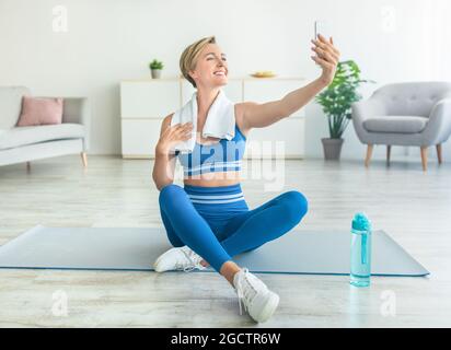 Smiling Middle-Aged Woman Exercising And Taking Selfie Stock Photo