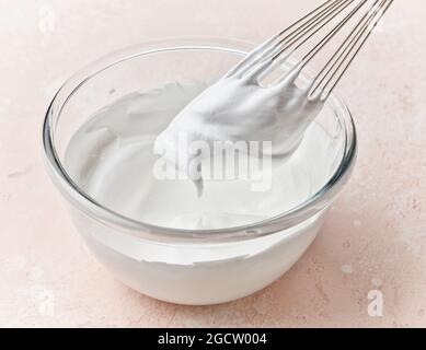 bowl of whipped egg whites on pink kitchen table top Stock Photo
