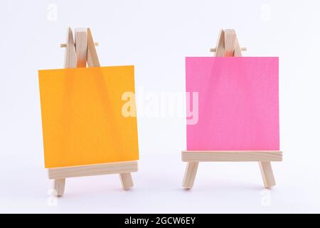 Two Wooden Easels Miniature with Blank Colored Square Canvas or Memo Paper - Mockup. Mini Wooden Stand with Clean Artboard on White Background, Copy Space Stock Photo