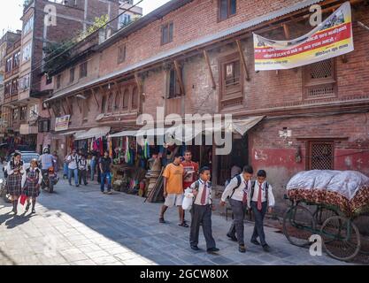 Nepalese schoolboys and schoolgirls in uniform coming home after school in Kathmandu, Nepal Stock Photo