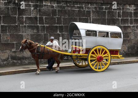 MANILA, PHILIPPINES - NOVEMBER 25, 2017: Driver stands by horse carriage in Intramuros district, Manila, Philippines. Horse tours are a popular touris Stock Photo