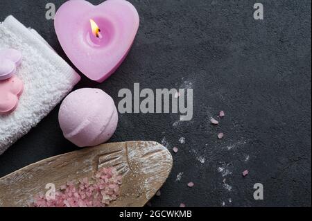 SPA still life, pink heart shaped bath bombs, salt with lit candle on concrete background. Flat lay, view from above Stock Photo