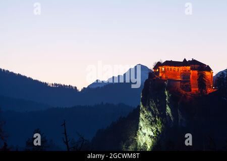 Bled castle (Blejski grad) with mount Triglav in the background at dusk Stock Photo