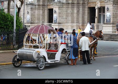 MANILA, PHILIPPINES - NOVEMBER 25, 2017: People stand by horse carriage in Intramuros district, Manila, Philippines. Horse tours are a popular tourist Stock Photo
