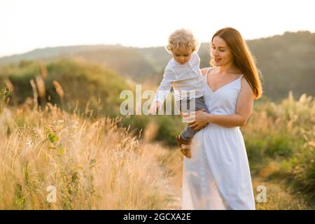 Woman shows beautiful nature to her little son. Mom with a boy in her arms against the backdrop of beautiful landscapes Stock Photo