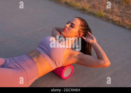 Young Caucasian woman doing exercise by foam roller at outdoors Stock Photo