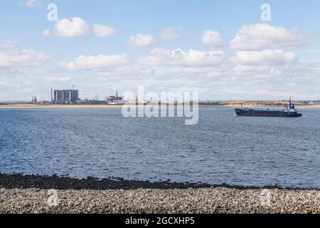 Hartlepool Nuclear Power Station and decommisioned oil rigs at Seaton Port as viewed from South Gare,Redcar,England,UK.Dredger approaches Teesport Stock Photo