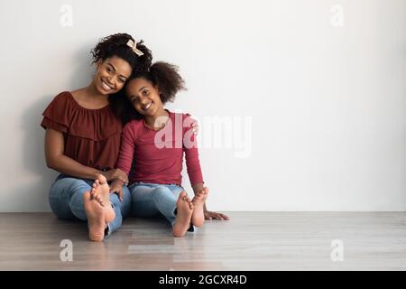 Adorable african american mother and daugher sitting on floor together Stock Photo