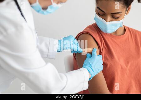 Nurse putting medical plaster on female patient arm Stock Photo
