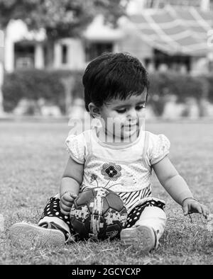 black and white portrait of cute indian baby girl playing in the park. Stock Photo