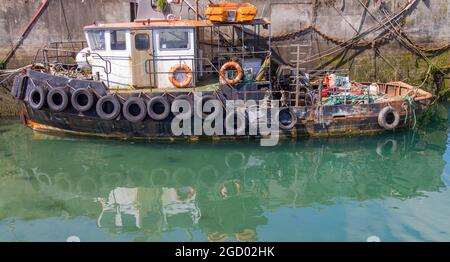 Old Tug Boat tied up alongside harbour  wall. Stock Photo