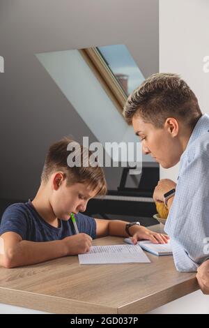 Kid boy doing homework at kitchen table with book Stock Photo