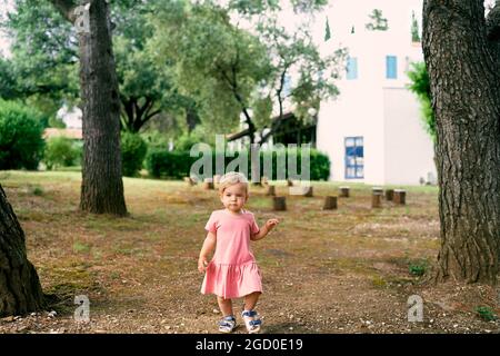 Little girl walks in a clearing near stumps in the courtyard Stock Photo