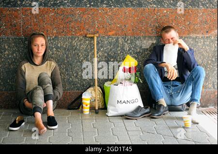 Two homeless young disabled girl and old man begging money sitting on the pavement in the underground passage. August 7, 2021. Kyiv, Ukraine Stock Photo
